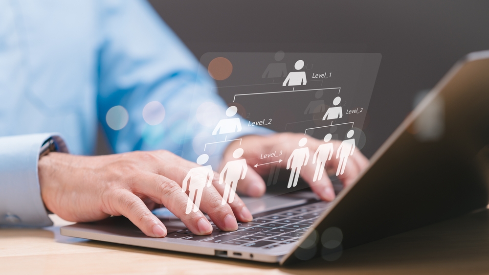 PCを操作する手元を映す写真。ピクトグラムなどで組織を表している。